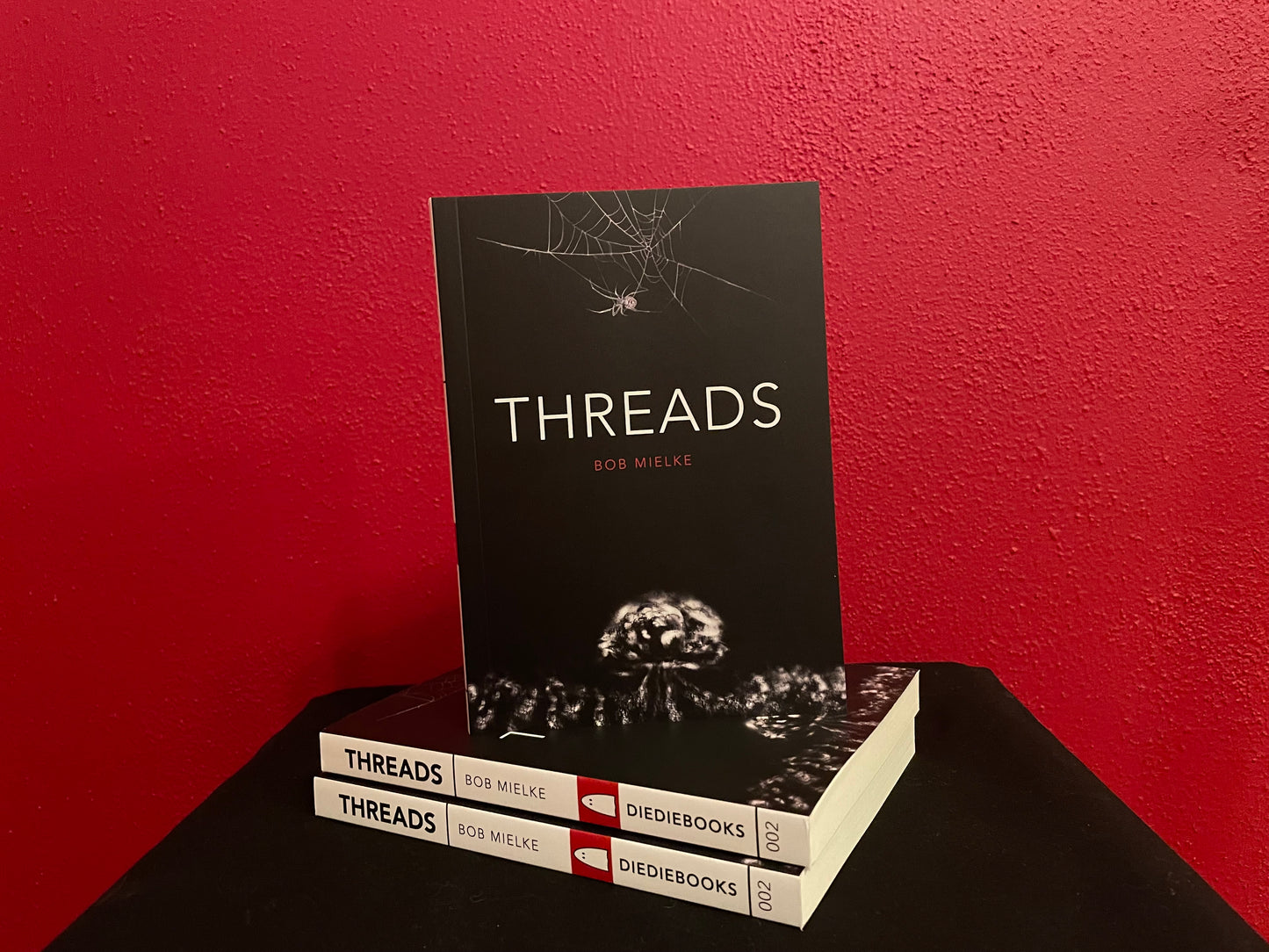 Image of three Threads books, two stacked on top of each other and one facing the camera